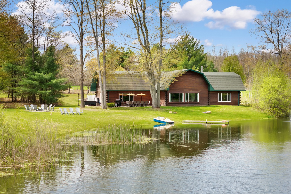 View of our home from the pond with paddleboat, fire pit and outdoor seating area and hot tub.