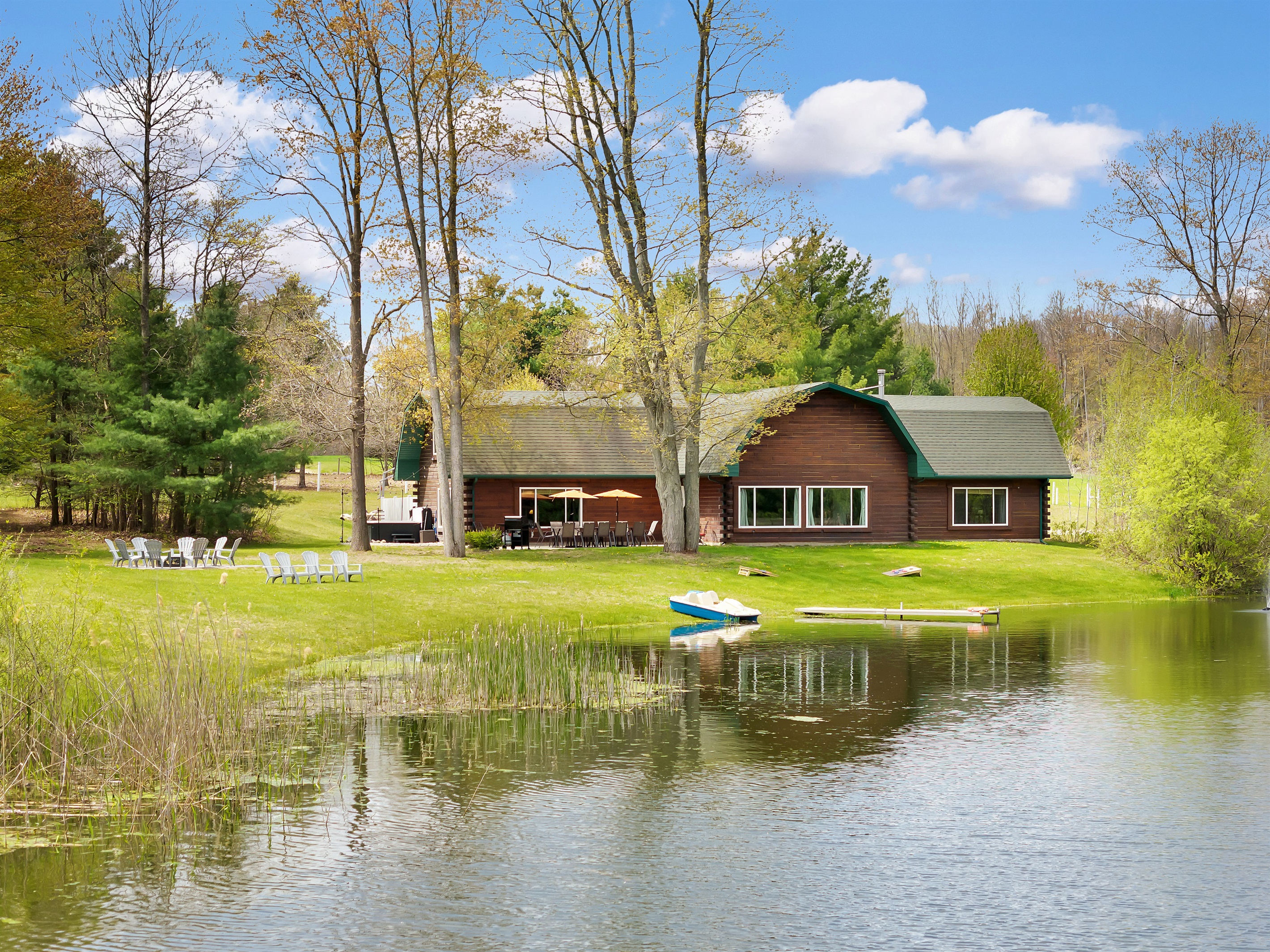View of our home from the pond with paddleboat, fire pit and outdoor seating area and hot tub.
