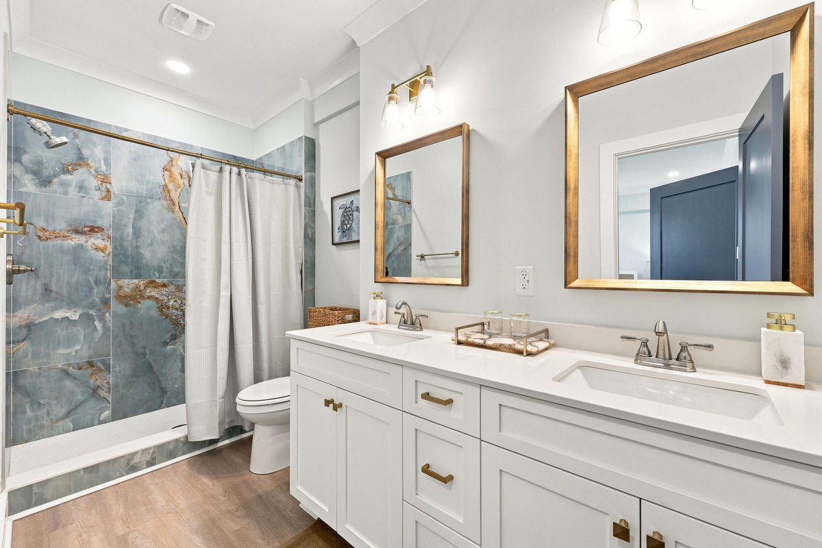 Ground level bathroom featuring a spacious double vanity, modern fixtures, and a stylish walk-in shower with coastal-inspired finishes