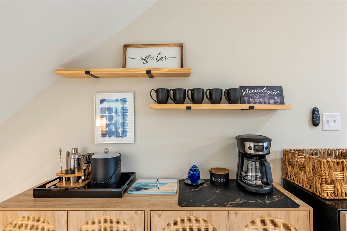 Enjoy the coffee bar provided during your stay! A stylish setup with black mugs, a coffee maker, and décor.