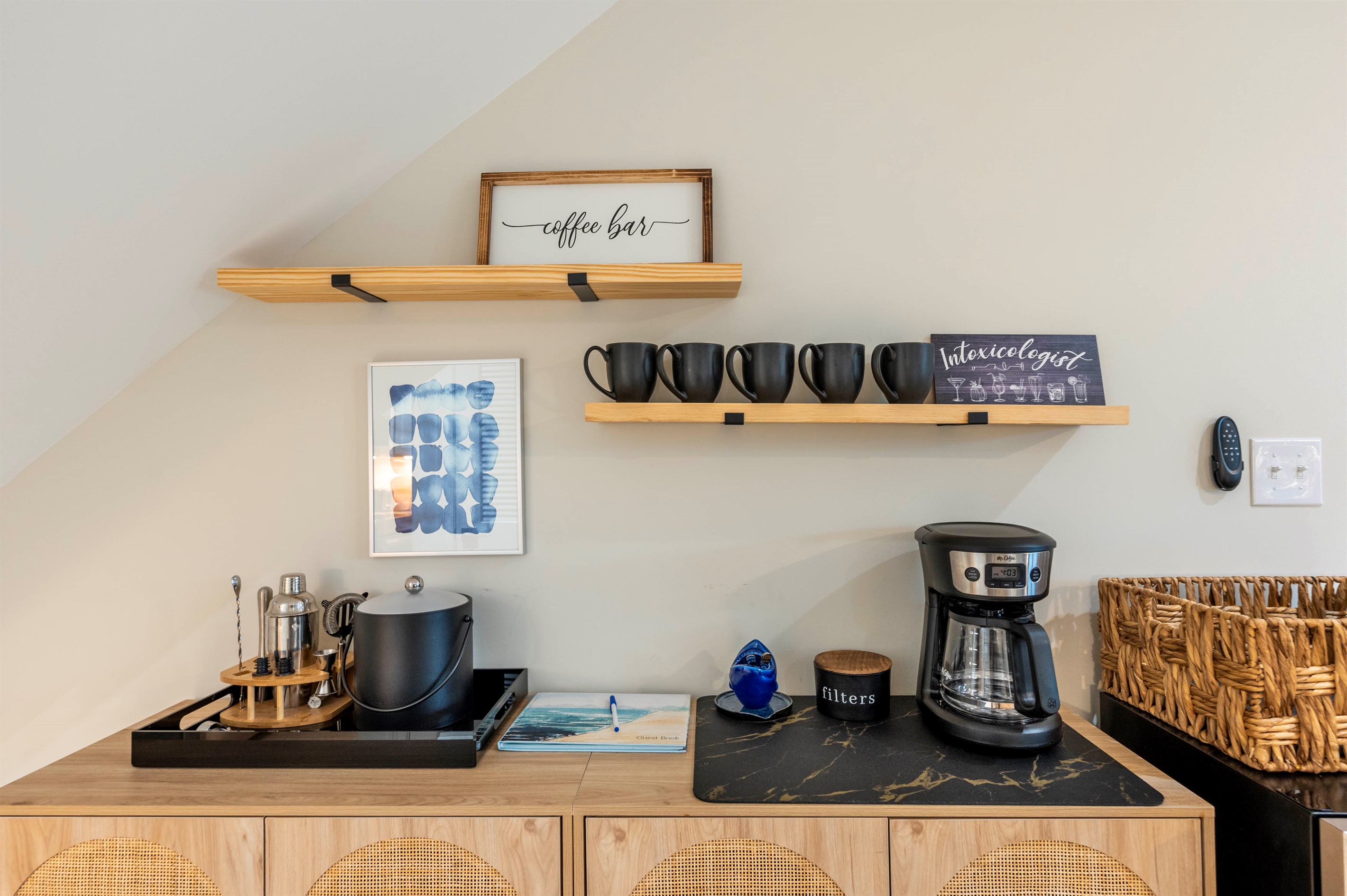 Enjoy the coffee bar provided during your stay! A stylish setup with black mugs, a coffee maker, and décor.
