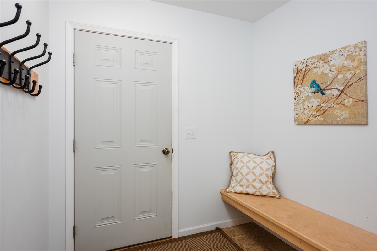 Garage entryway with bench, coat hooks, and storage