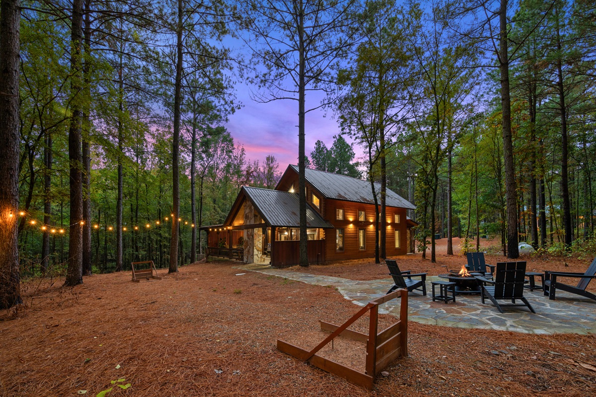 Charming exterior view of Wolf Creek glowing in the forest at dusk.
