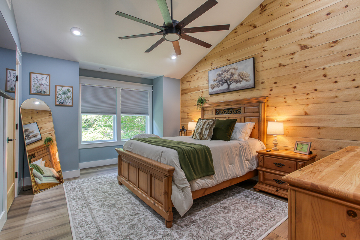 Relax in this upstairs queen bedroom at Robbin’s Nest on Snowbird Creek, with a vaulted ceiling, warm wood accents, and an inviting reading chair.