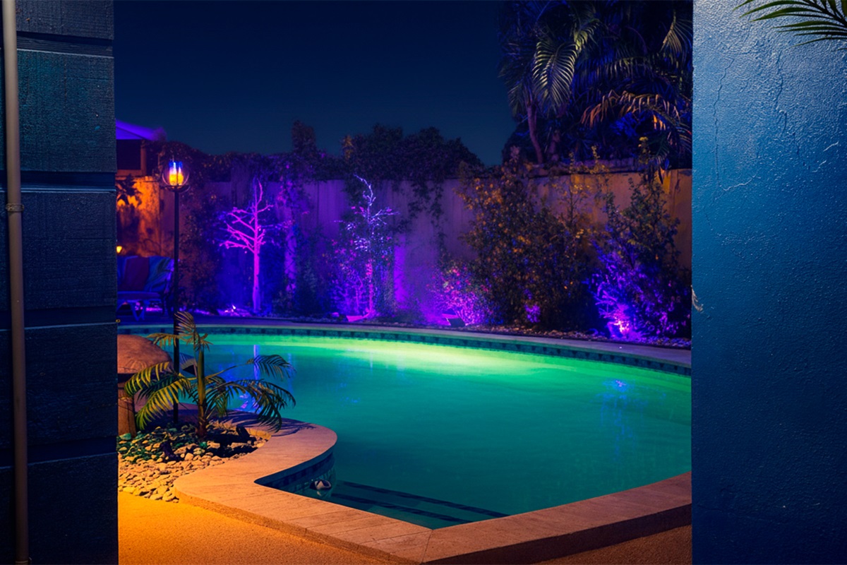 Architectural night view of the pool framed by tropical landscaping and ambient lighting.