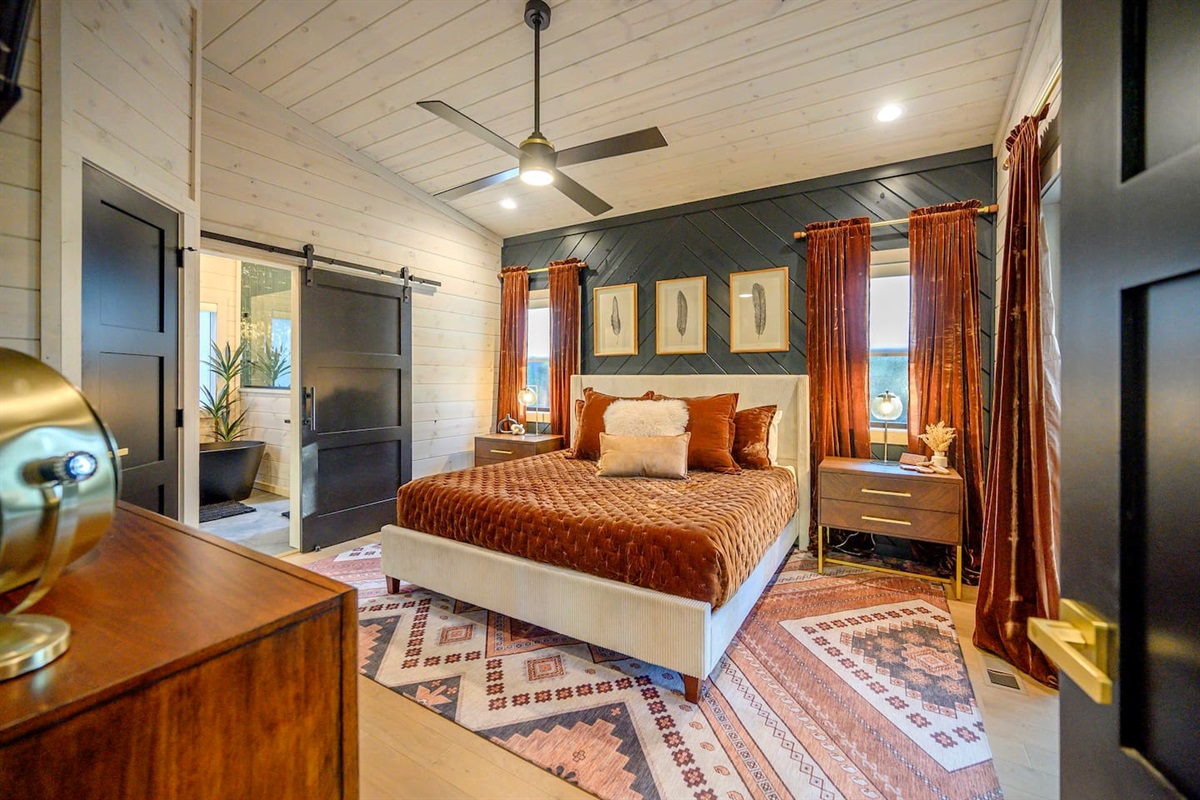 The primary bedroom features a plush king size mattress and lines, with velvet comforter and matching pillows and drapes.  The attached spa inspired bathroom provides a relaxing place to soak in the tub or shower.