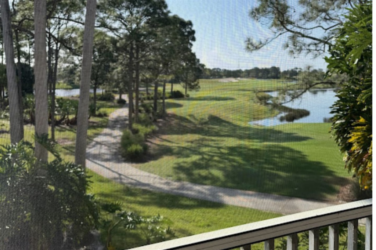 Peaceful balcony view overlooking green space, walking path, and water views.