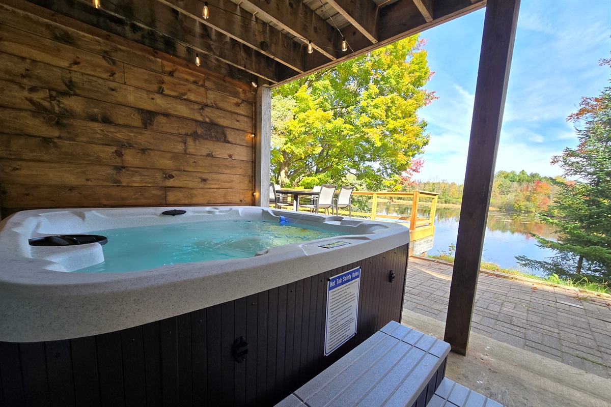 Unwind in our covered lakeside hot tub with stunning views! ✨ Enjoy bubbling water, peaceful nature, and vibrant trees—perfect for sunrise coffee or a relaxing sunset soak. 🌲🌅