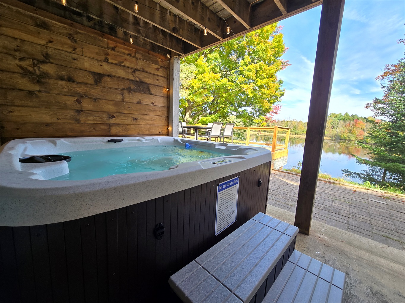 Unwind in our covered lakeside hot tub with stunning views! ✨ Enjoy bubbling water, peaceful nature, and vibrant trees—perfect for sunrise coffee or a relaxing sunset soak. 🌲🌅
