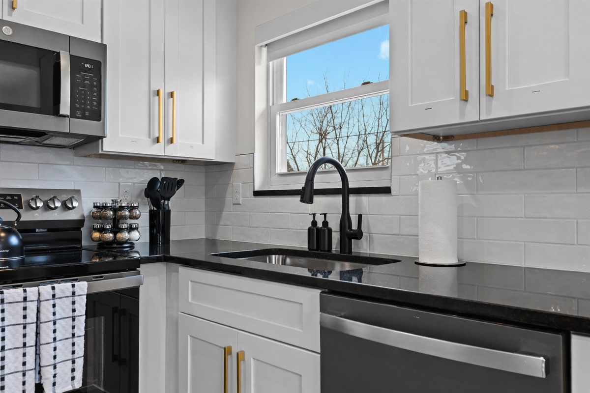 Clean, modern kitchen details with quartz counters, matte black fixtures, and bright window light—stylish, functional, and ready for everyday cooking.