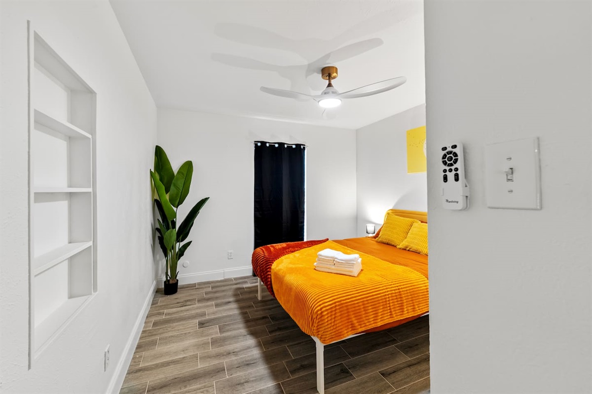 Bright bedroom with cozy orange bedding, blackout curtains, and ample closet space—perfect for restful nights and relaxed mornings.