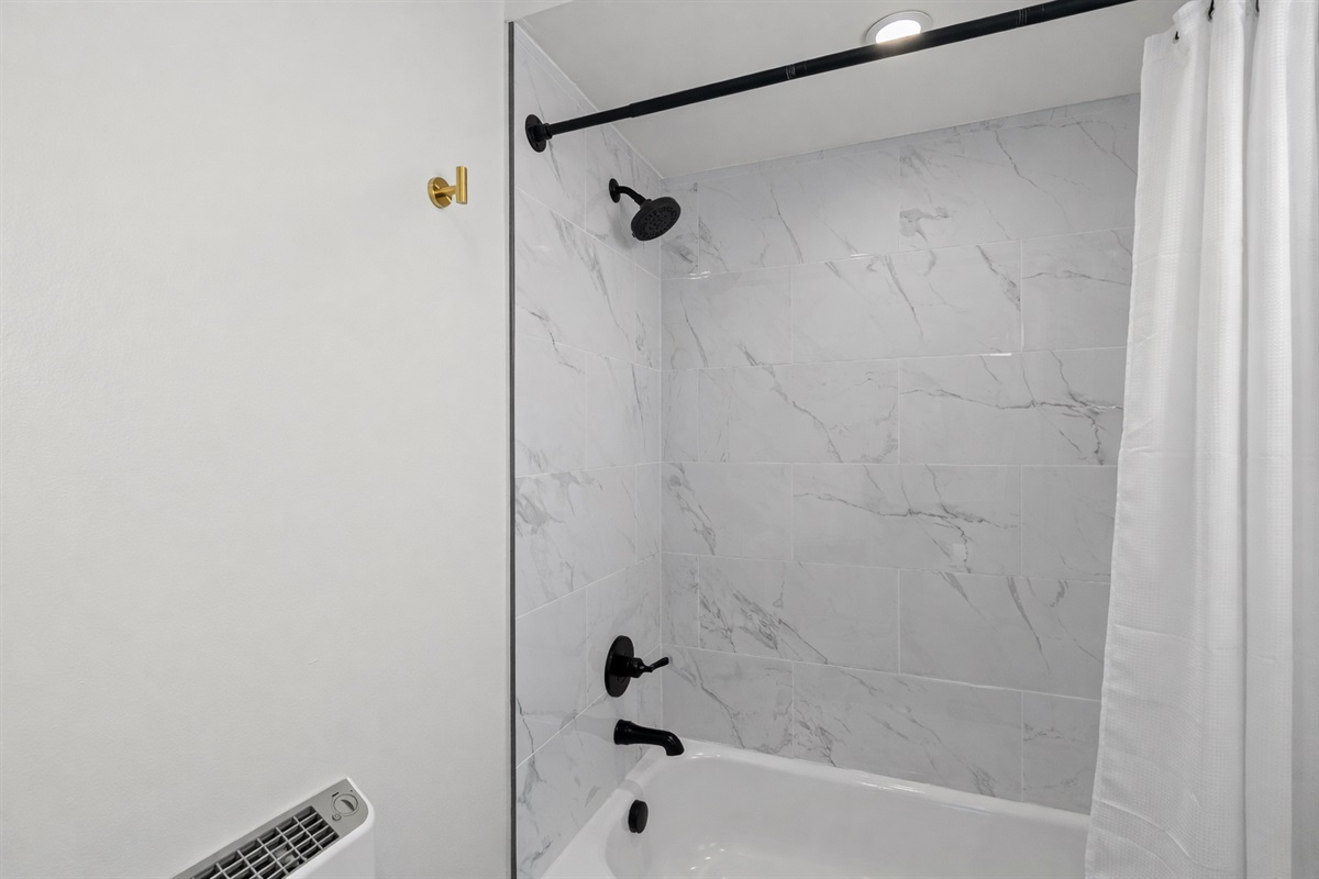 Sleek tub-shower combo with modern tile, matte black fixtures, and a clean, spa-like feel—perfect for unwinding after a long day.