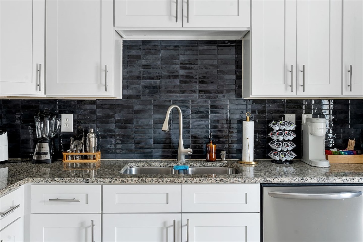 Enjoy the convenience of a fully equipped kitchen with a sleek sink area and ample counter space. The stylish backsplash complements the modern fixtures.