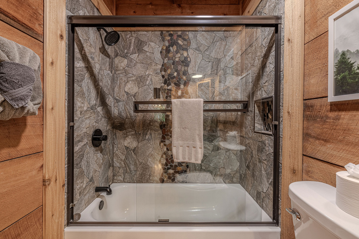 Stone shower, soaking tub, windows facing the woods.