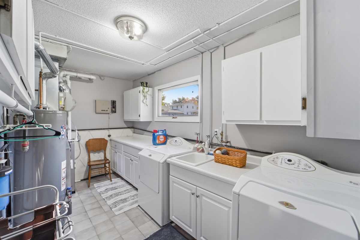 Fully stocked laundry room with front load washer and dryer, ironing board, and utility sink is located in the walk-out basement.