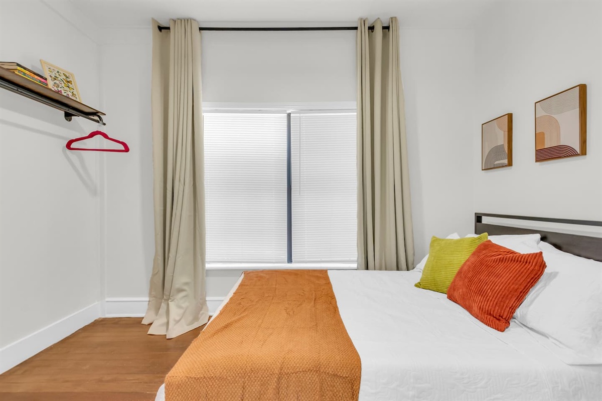Bedroom with cozy full bed, clothing rack, hangers and fresh decor.