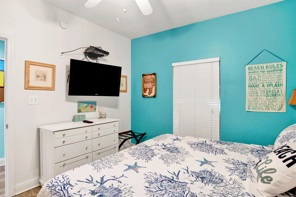 2nd bedroom with king bed, dresser, wall mounted 40" tv with a firestick, ceiling fan, 2 nightstands and direct main bathroom access through door in the bedroom