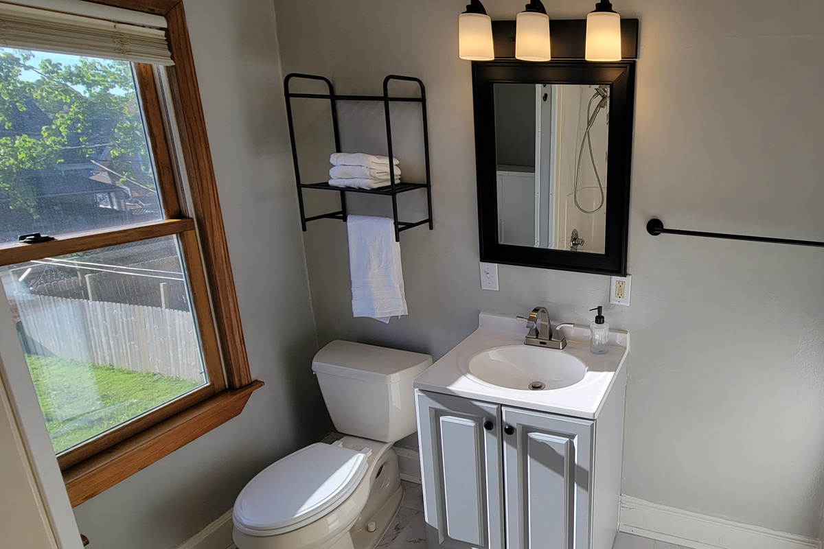 Clean bathroom with fresh towels, sink, mirror, and toilet.