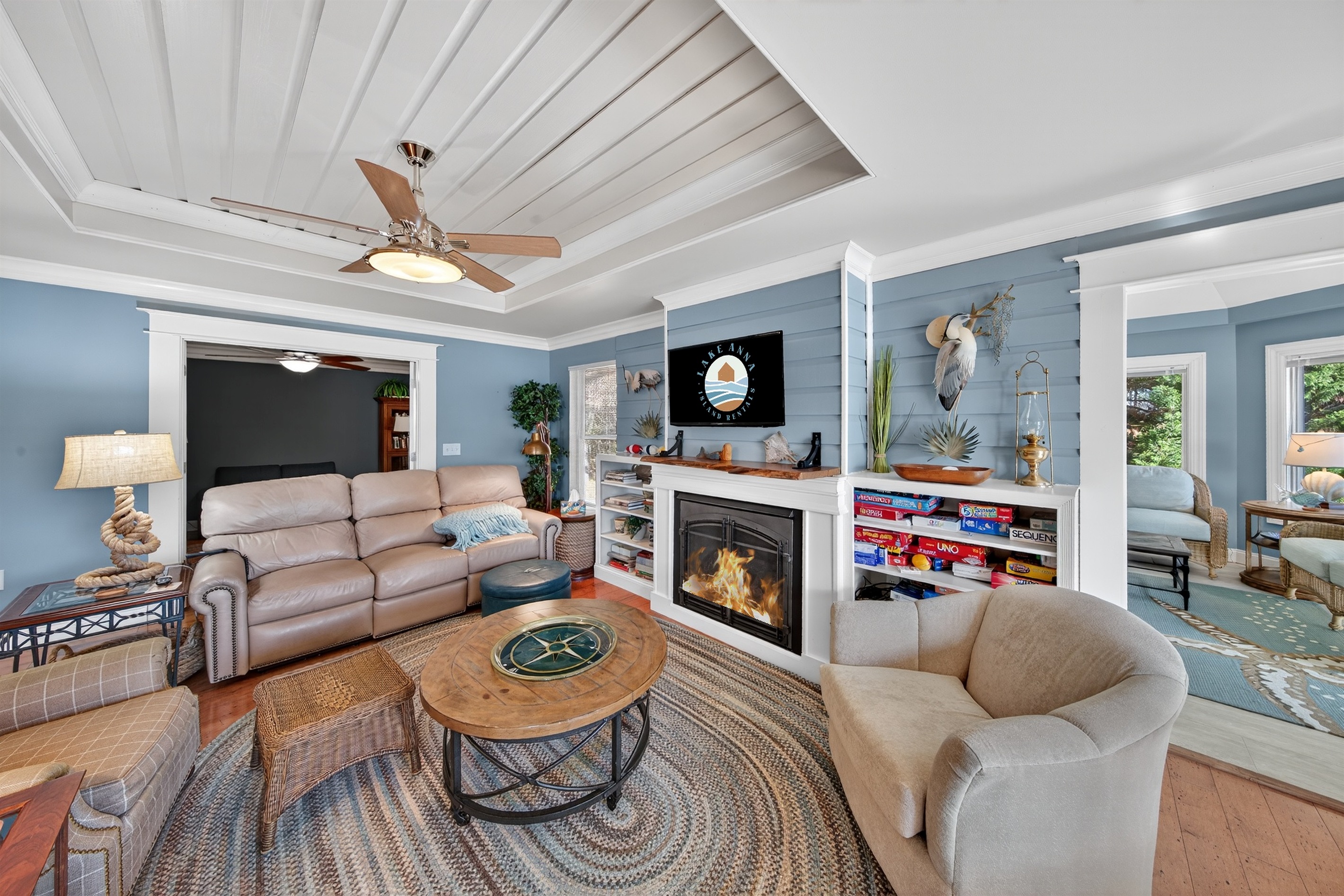 A warm and welcoming living space with a fireplace, games, and a bright open layout that connects effortlessly to the kitchen.