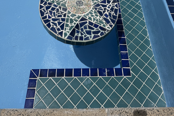 The pool features a unique in-water mosaic table and stepped seating area, perfect for a refreshing dip and conversation.