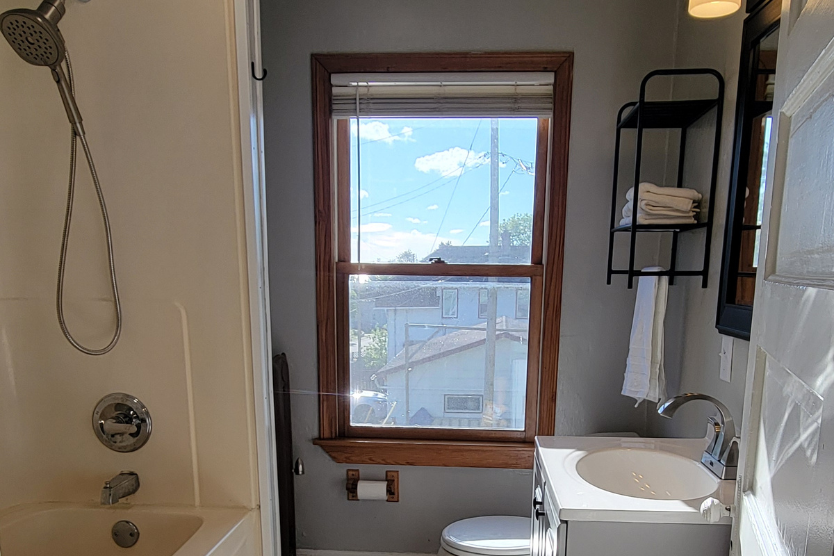 Bathroom with full tub/shower combo, sink, mirror, and fresh towels.
