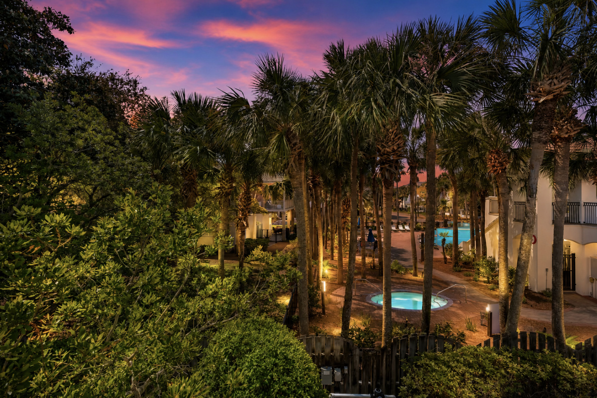 Glimpses of the community pool and hot tub among swaying palm trees from the balcony