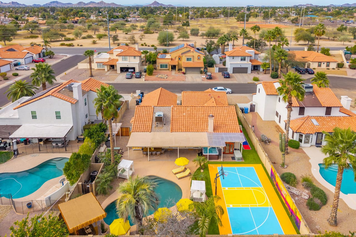 An aerial view says it all — pool, putting green, lounge seating, and desert views across this resort-style backyard.