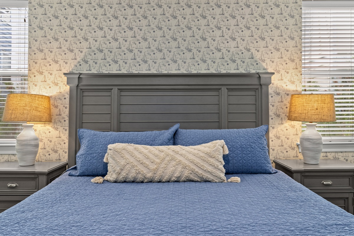 A queen bed retreat with coastal wallpaper and soft blue tones
