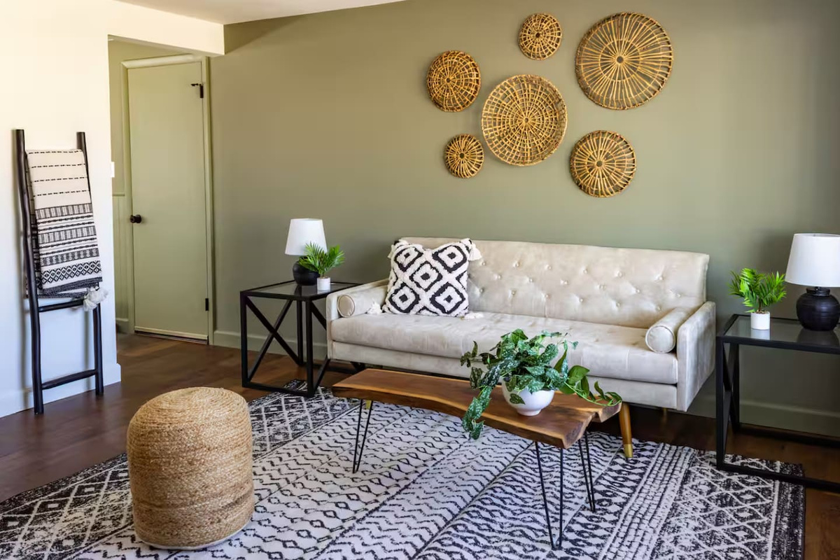 Warm olive walls, woven wall art, and a plush sofa make this living room feel like a curated escape.