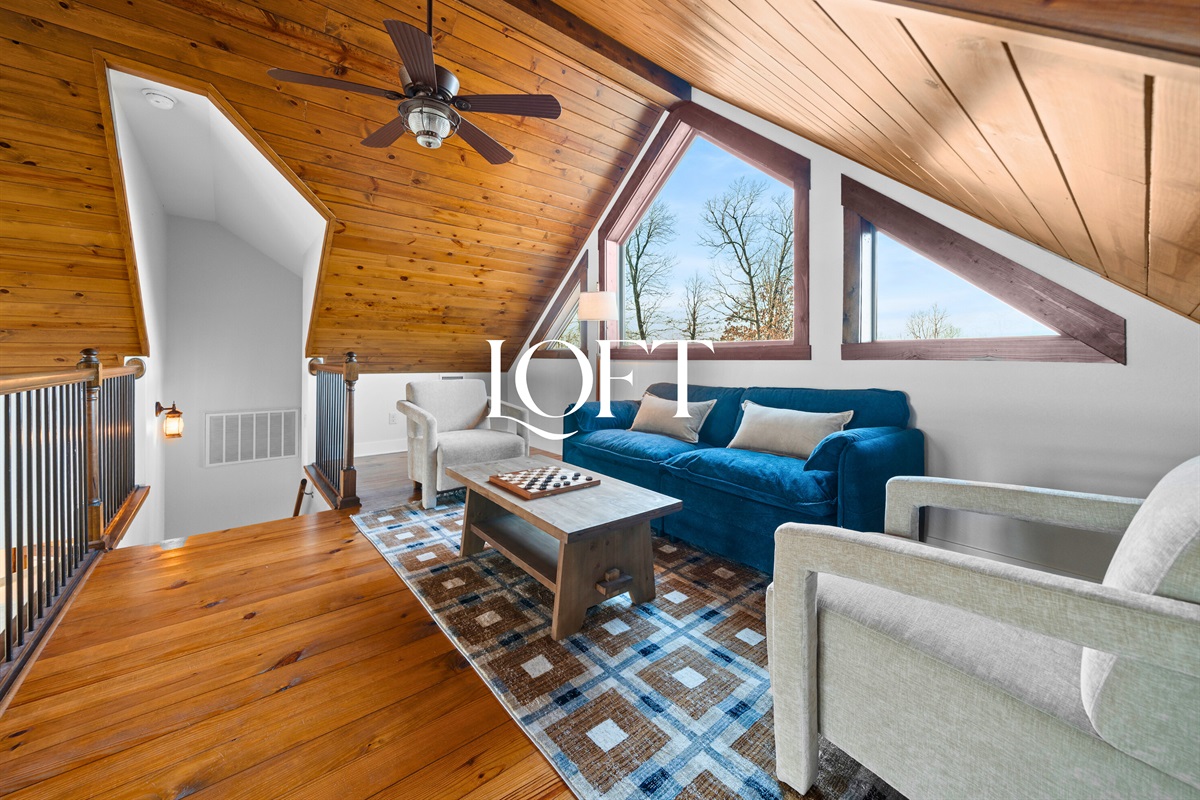 The loft provides a cozy upper-level escape with warm wood ceilings and a comfortable seating area overlooking the main living space.