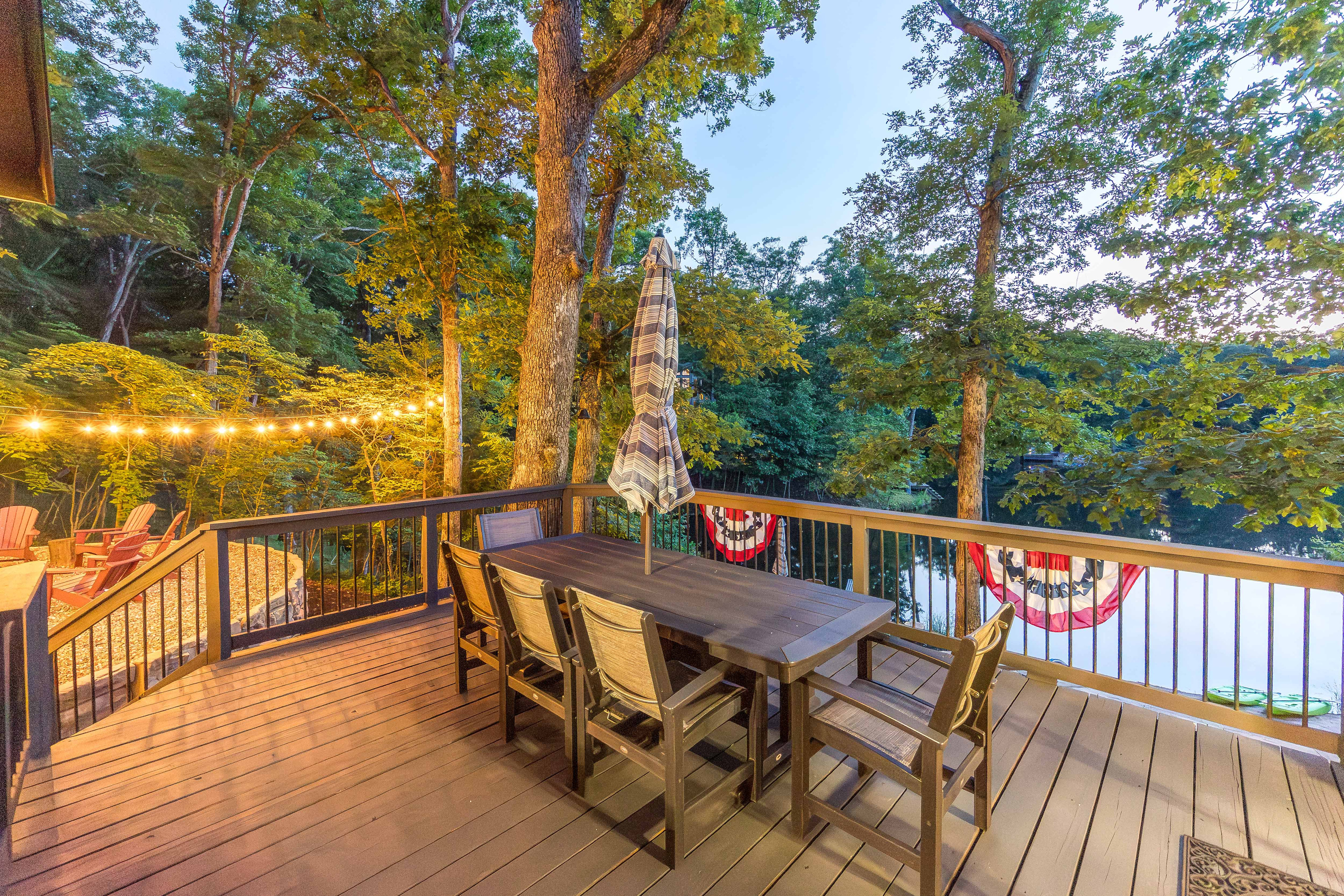 Outdoor dining surrounded by trees and overlooking the water.