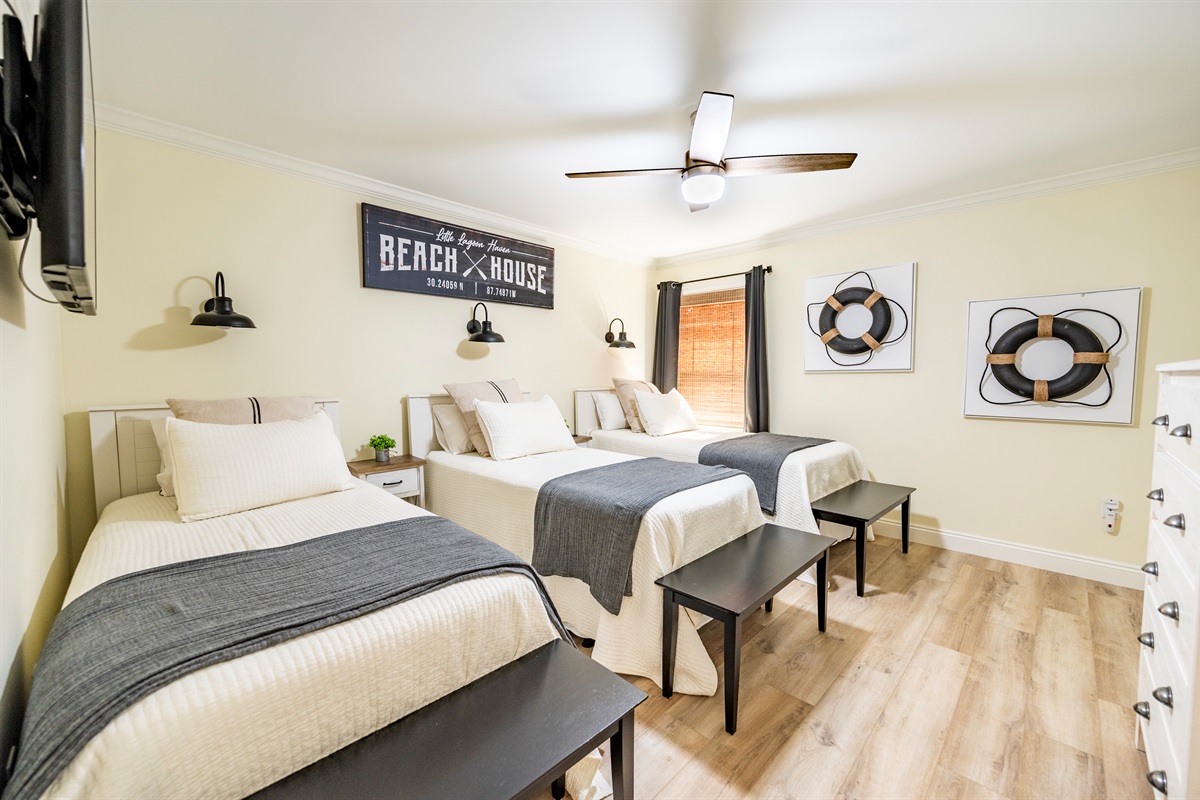 Cozy beach house bedroom with three comfy beds and coastal-inspired decor.