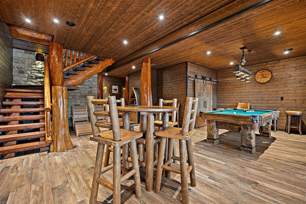 Warm and inviting entertainment space with handcrafted log accents, full-size pool table, and walk-out access to the lakefront.