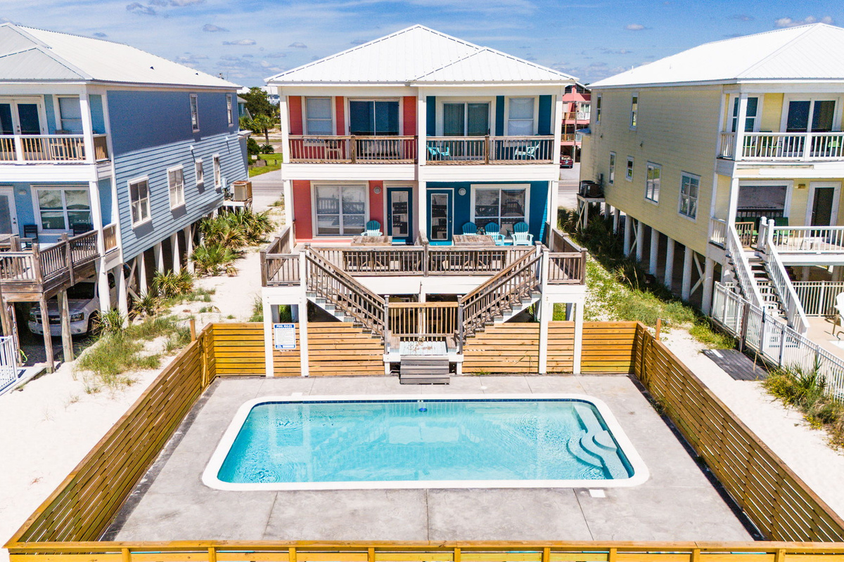 Drone view of the vacation property highlighting the private swimming pool, outdoor entertaining area, and surrounding coastal homes.