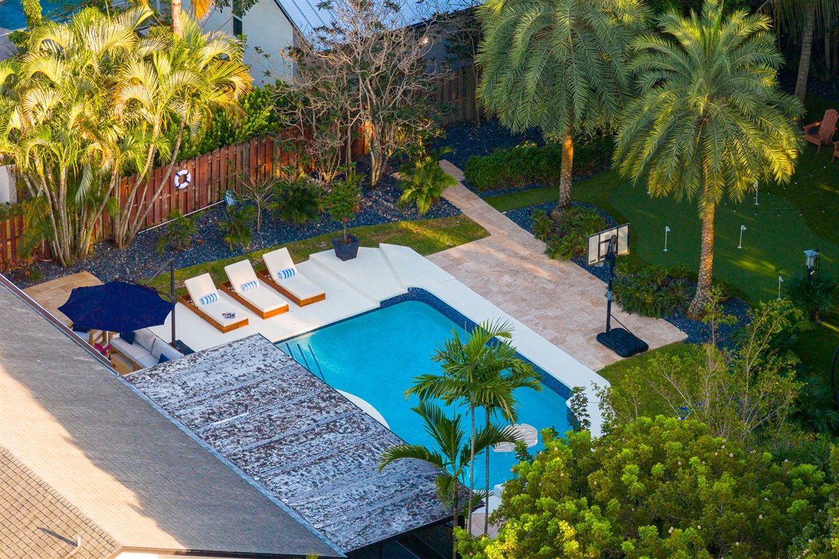 A sun-soaked retreat featuring a sparkling pool, surrounded by lush landscaping and tropical vibes.