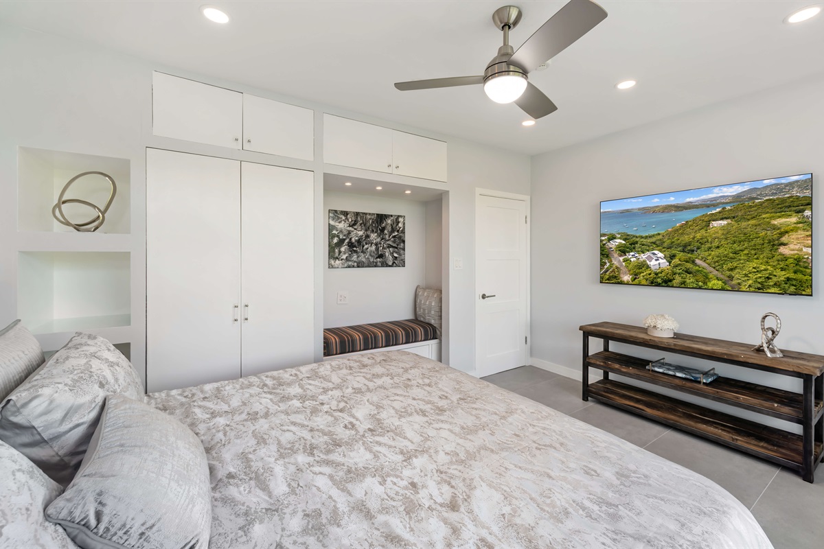 This guest room has a Smart TV, ceiling fan and little seating nook