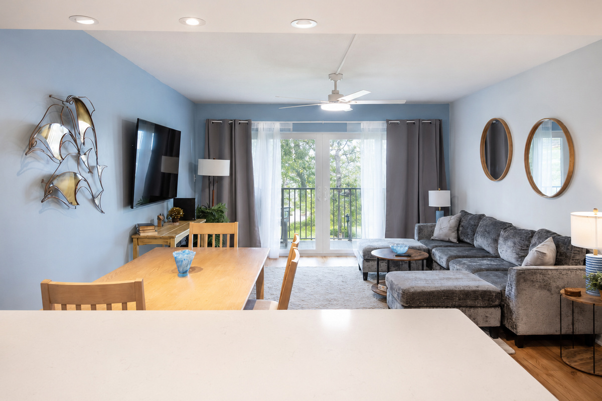Modern living room with gray sectional, blue accent wall, and dining area view.
