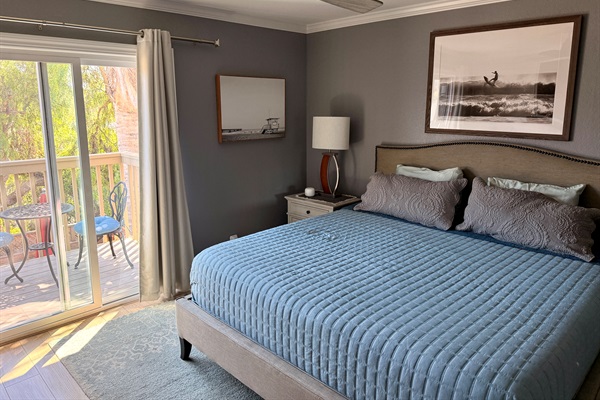 Primary bedroom with sliding door to balcony overlooking the yard and mountains.