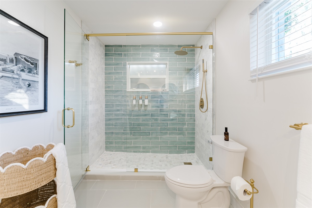 Spa-inspired ensuite with a walk-in glass shower, soft sage tile, and brushed brass fixtures. A double vanity with designer mirrors creates a bright, hotel-style retreat made for slow mornings and effortless luxury.