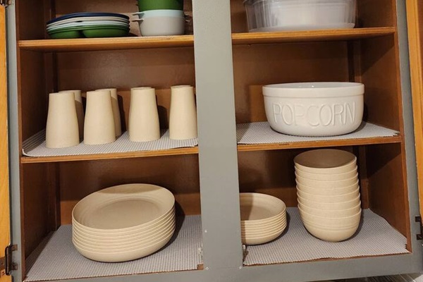Kitchen stocked full of regular and plastic dishes for outdoor usage.