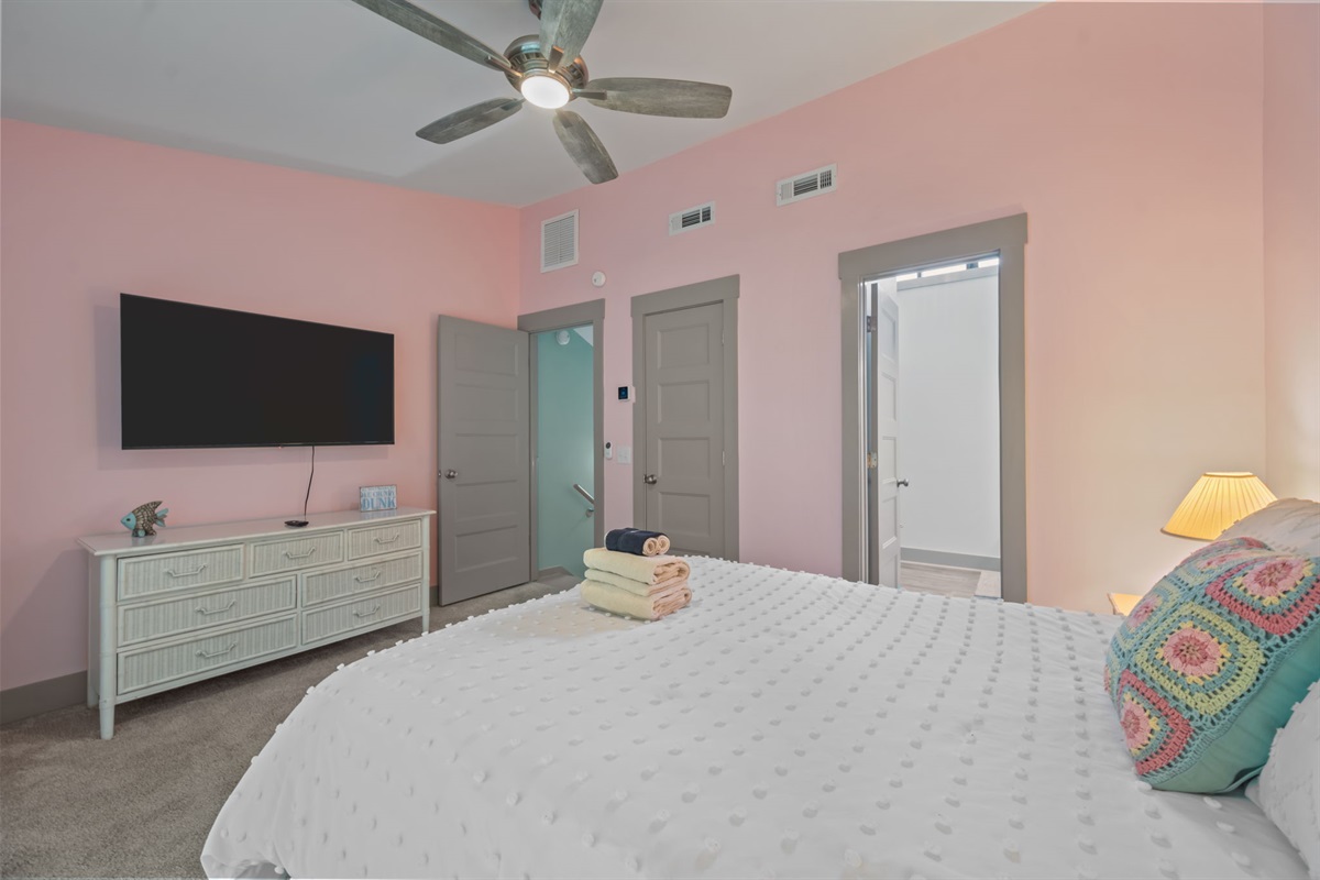 Spacious Master bedroom featuring a Queen bed, ceiling fan, and mounted TV: your private, relaxing escape after a full day at the coast!