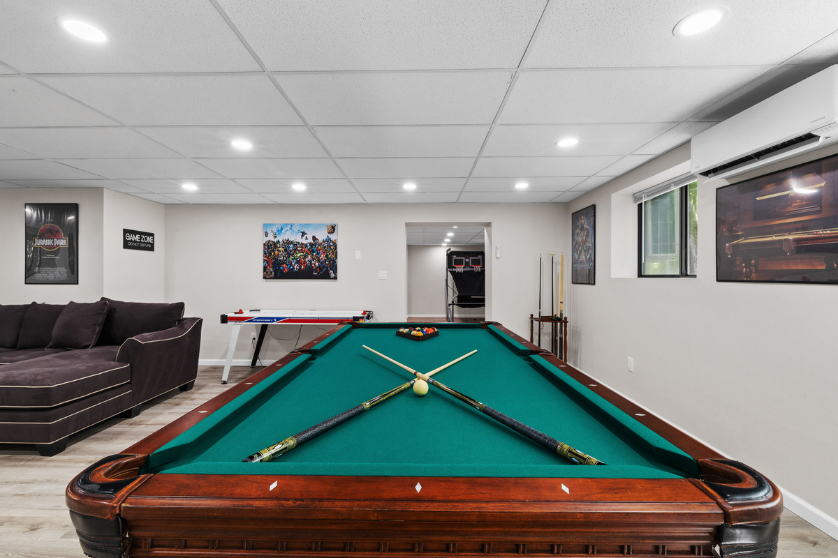 A professional-grade pool table stands as the centerpiece of the room, perfect for hosting friendly tournaments