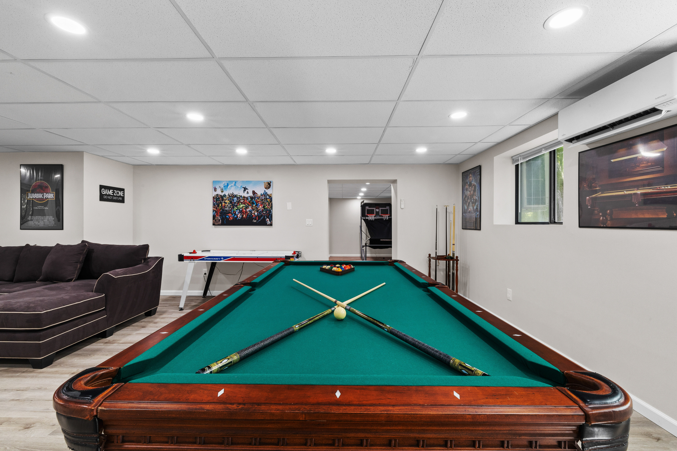 A professional-grade pool table stands as the centerpiece of the room, perfect for hosting friendly tournaments