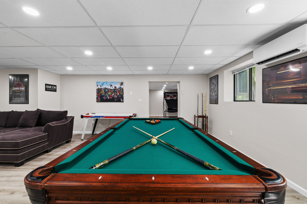 A professional-grade pool table stands as the centerpiece of the room, perfect for hosting friendly tournaments