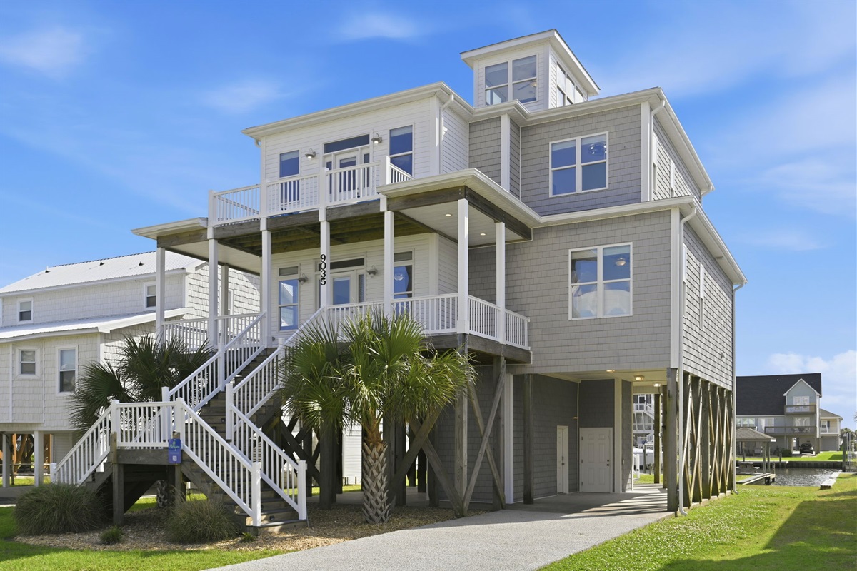 Elevated beach house with canal access, expansive outdoor spaces, and a private driveway