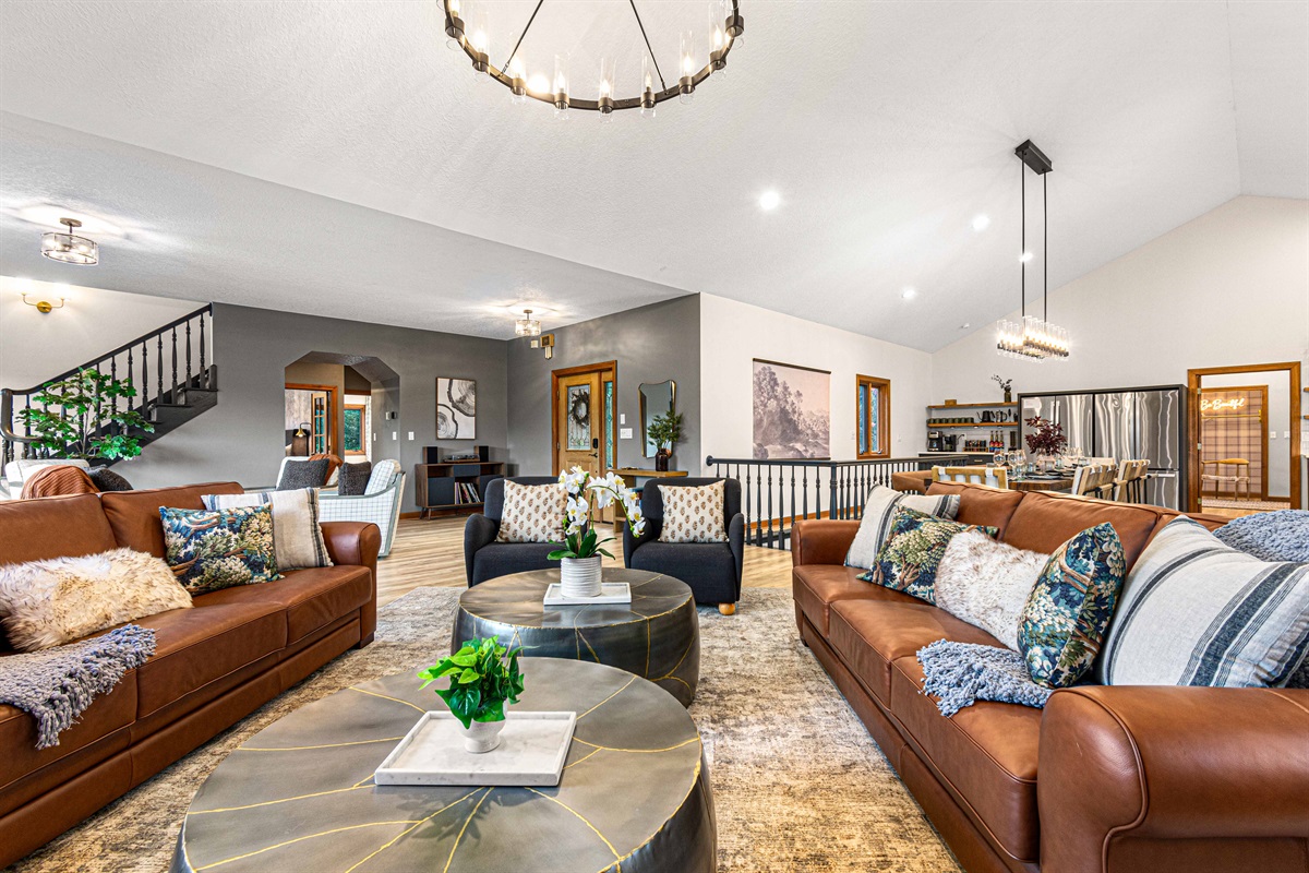 Spacious open-concept living—gather on plush leather sofas beneath elegant chandeliers, with seamless flow into the dining area for effortless entertaining.🛋️✨🍷