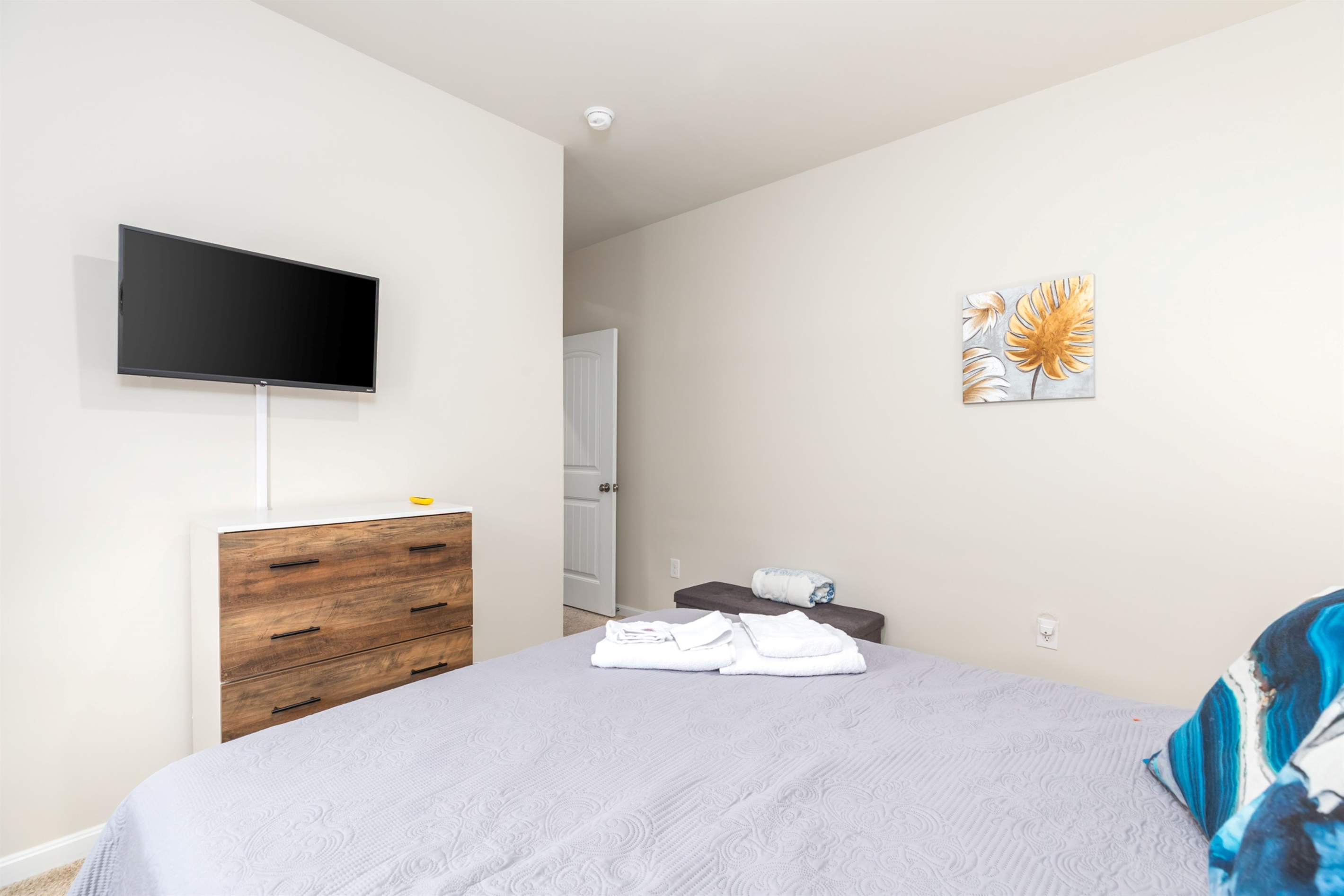 Welcome to our deluxe master suite! Relax with a 50" smart TV, a plush sitting bench at the king bed's foot, handy USB outlets for phone charging, a cozy corner chair, and a gentle ceiling fan