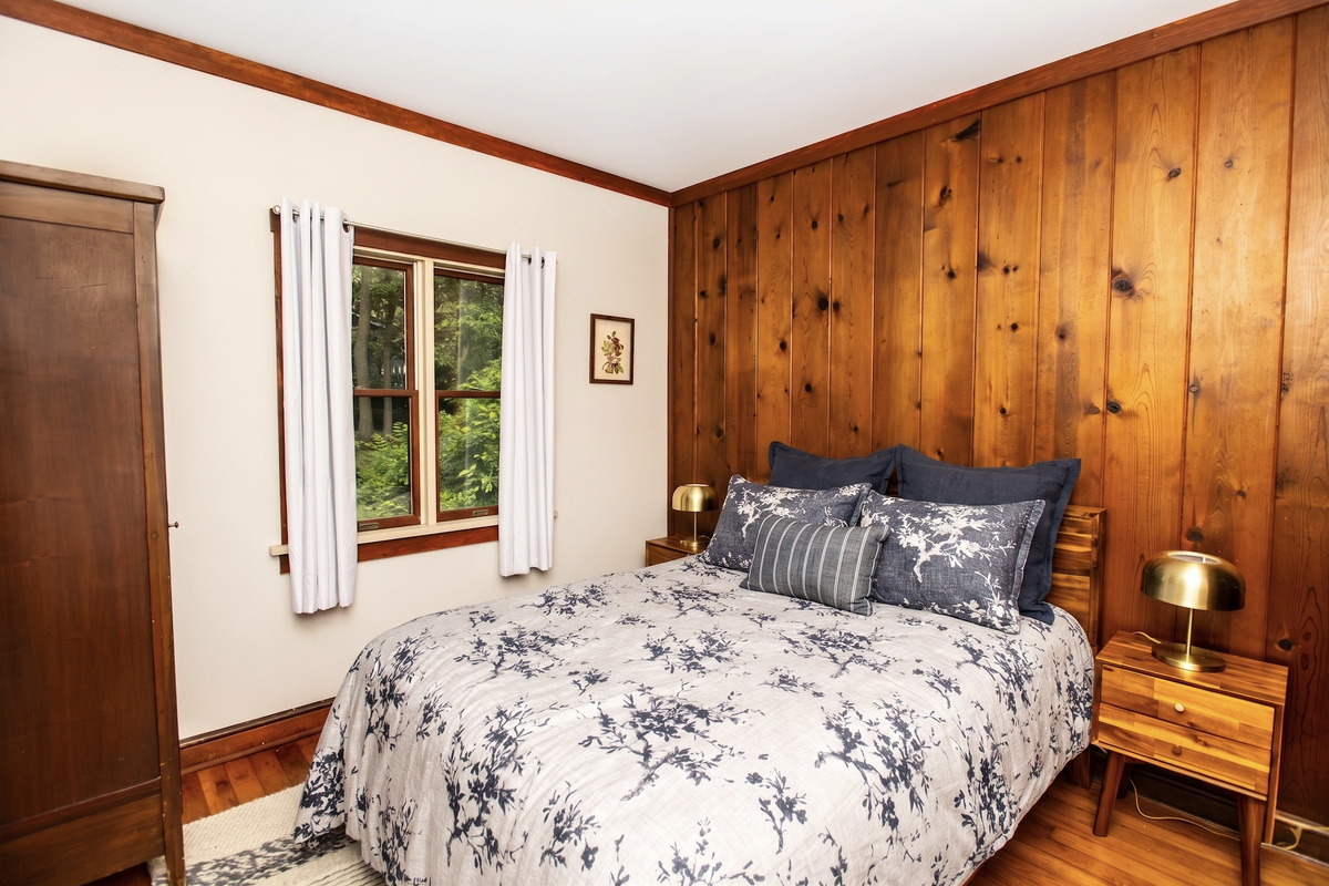 Peaceful bedroom with a plush queen bed and knotty pine accent wall