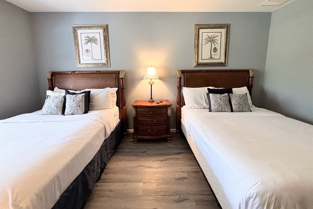 Cozy bedroom with two comfortable beds, matching nightstand, and simple neutral decor.