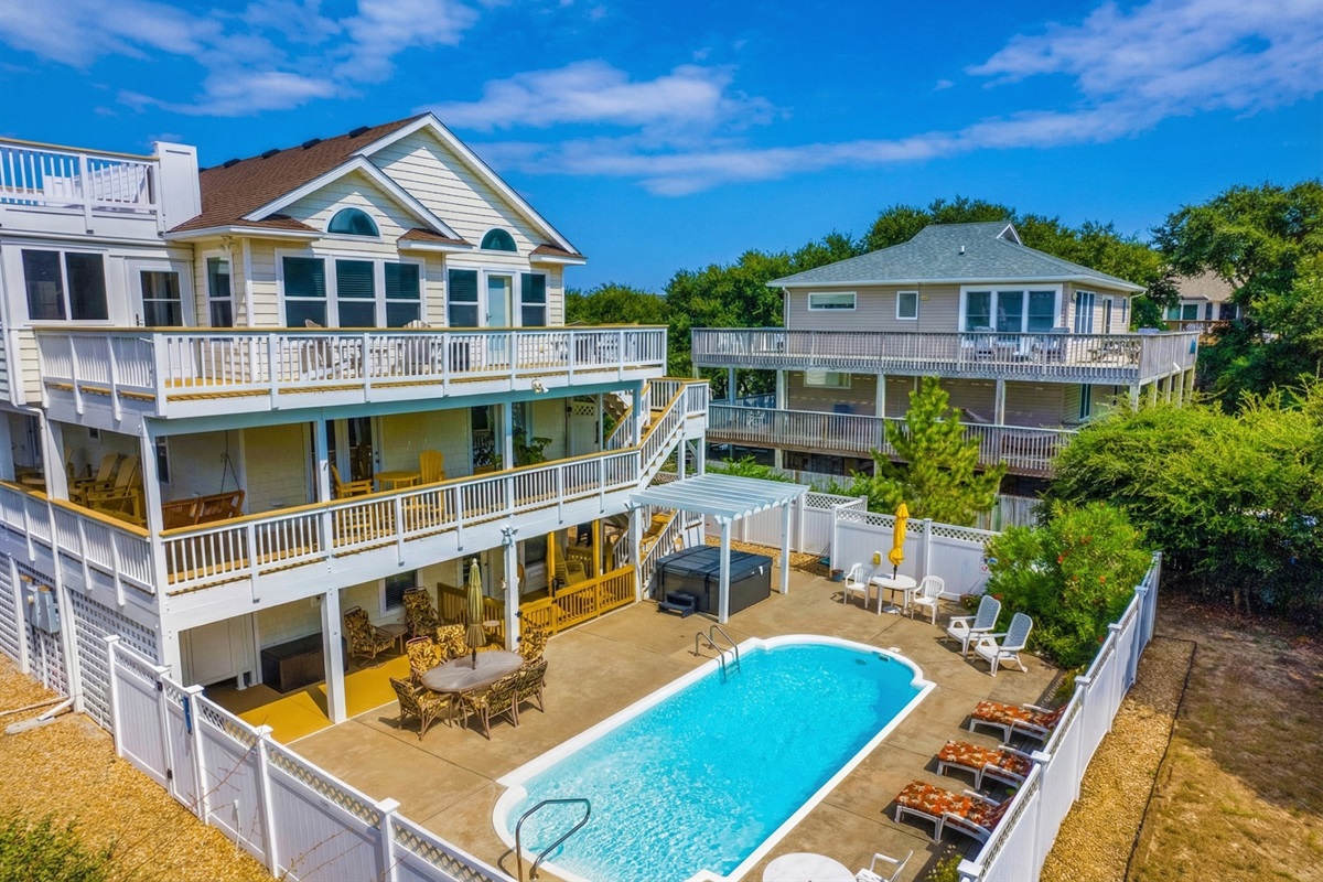 A high-angle view of the private backyard retreat, displaying the kidney-shaped swimming pool, sun loungers, and spacious paved deck.